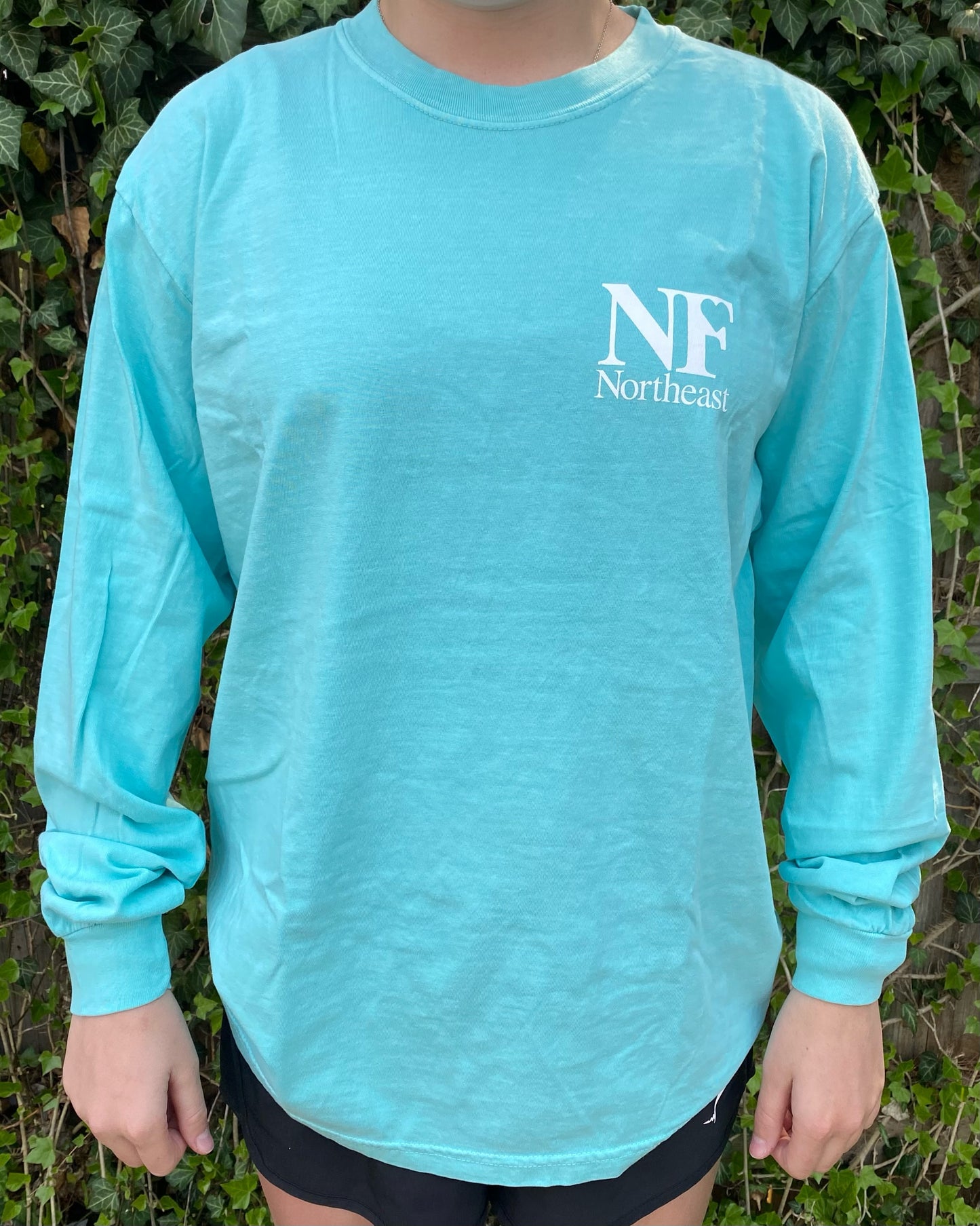 long sleeve teal shirt on woman with NF Northeast logo printed on upper left chest