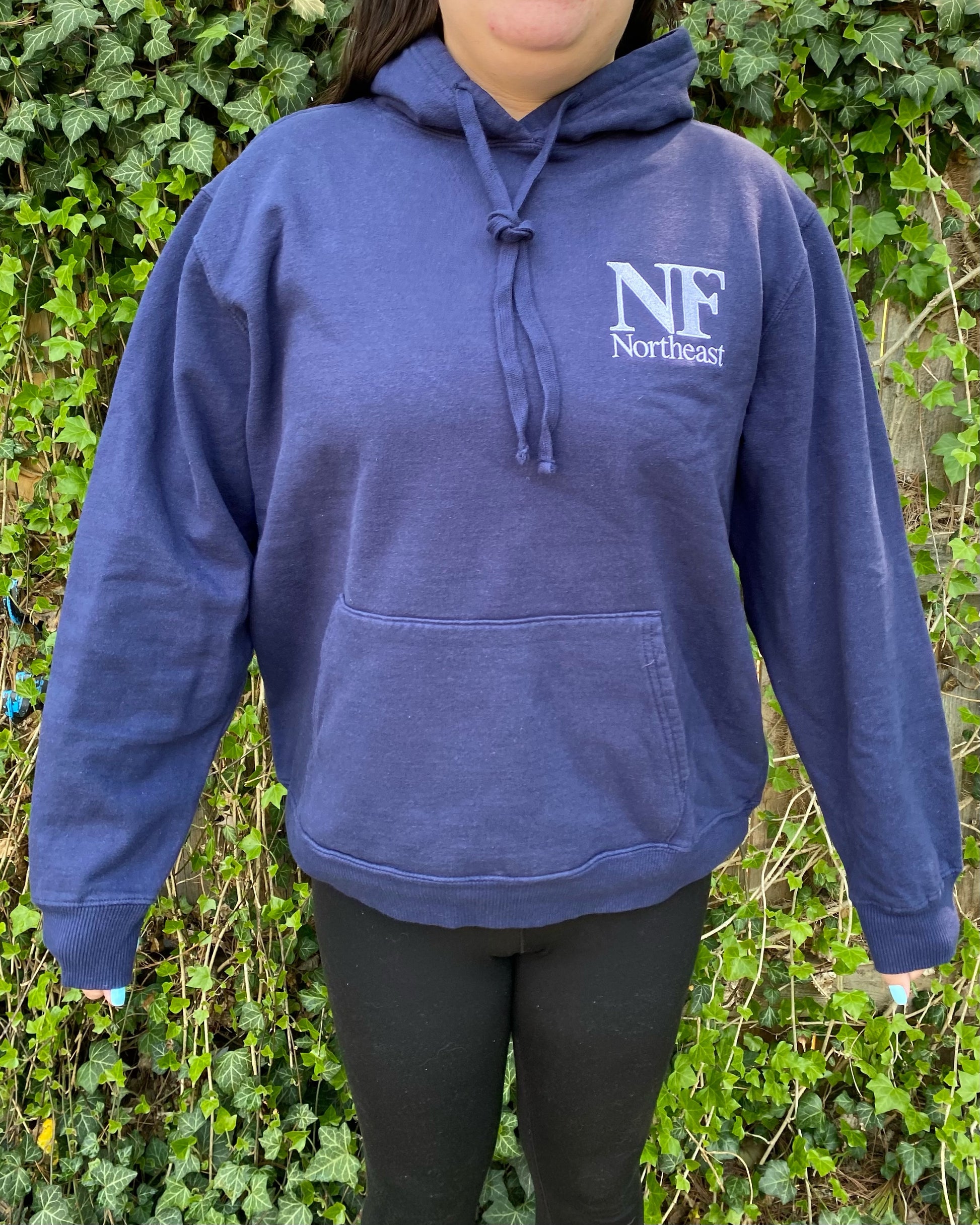 navy blue hoodie with front pocket on woman with NF Northeast logo embroidered on upper left chest