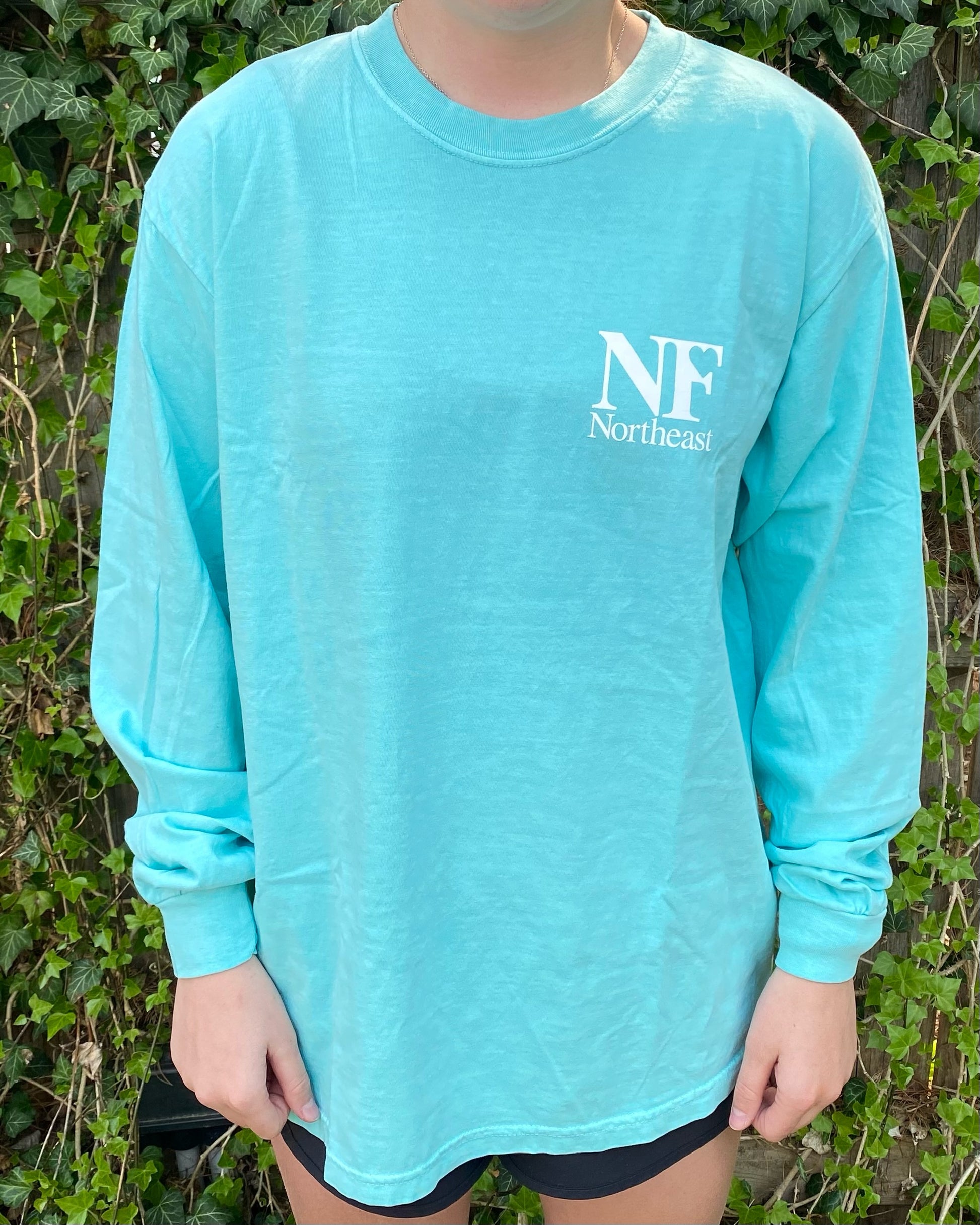 long sleeve teal shirt on woman with NF Northeast logo printed on upper left chest