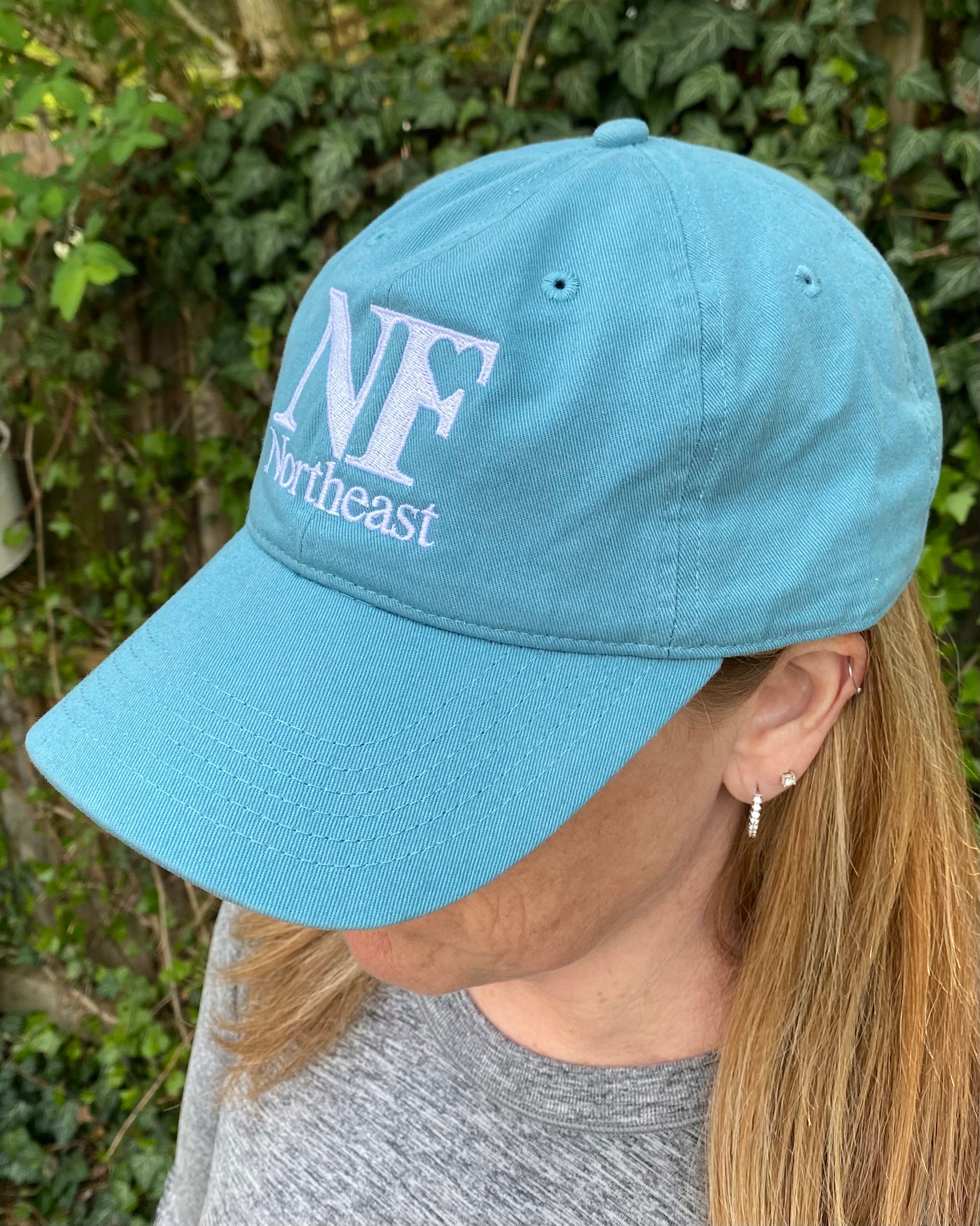 image of teal baseball cap from side with NF Northeast logo embroidered on front of cap